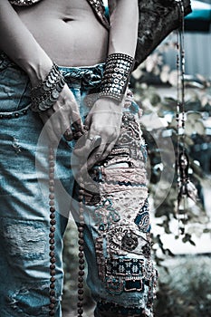 Young woman in embroidered blue jeans boho style hands with bracelets and rings summer fashion
