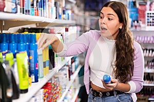 Young woman emotionally choosing spray in cosmetics store
