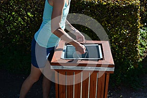 Young woman emptying a trash can in the park. it is her job or a summer job in a municipal gardening company serving citizens. hol