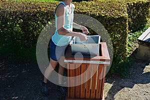 Young woman emptying a trash can in the park. it is her job or a summer job in a municipal gardening company serving citizens. hol