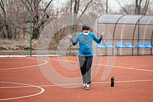 A young woman is engaged in jumping rope in a medical mask. Protection from coronavirus infection with a medical mask