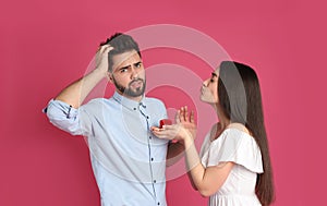 Young woman with engagement ring making marriage proposal to her boyfriend on crimson background