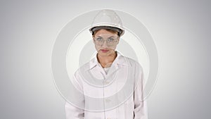 Young woman engineer in hard hat walking on gradient background.