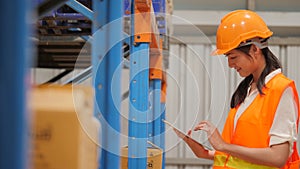 Young woman engineer using digital tablet checking stock in industrial warehouse