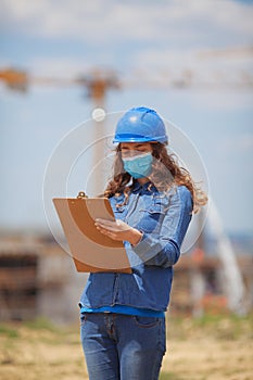 young woman engineer wearing face mask while working in construction site