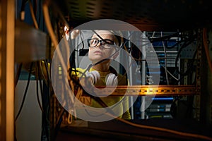 Young woman IT engineer working in datacenter room connecting cables