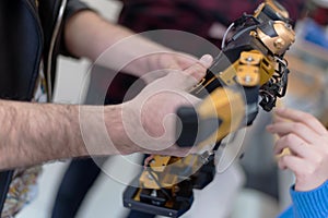 Young woman engineer working on robotics project. Scientist engineer designs small human robot, settings artificial intelligence