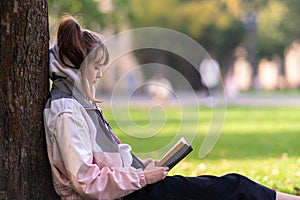 Young woman engrossed in reading a book outdoors