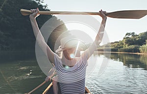 Young woman enjoy boat ride and hold oars high