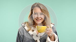 Young Woman Enjoying the Aroma of Fresh Coffee in Polka Dot Robe, Turquoise Background