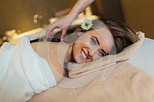 Young woman is enjoying back stone massage at spa
