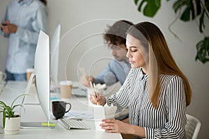 Young woman enjoying chinese food box during office lunch break