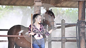 Young Woman enjoying the company of her horse in a stable and smiling. A Woman with her horse