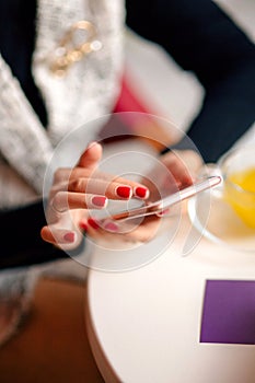 Young woman enjoying a cup of tea at cafe while using smartphone.. Lady drinks hot tea and texting. Teengirl drinking