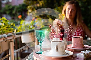 Young woman enjoying a cup of Turkish coffee served outside with water flowers and delight dessert in romantic setup on glass