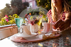 Young woman enjoying a cup of Turkish coffee served outside with water flowers and delight dessert in romantic setup on glass