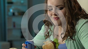 Young woman enjoying her burger and looking at it with admiration during movie