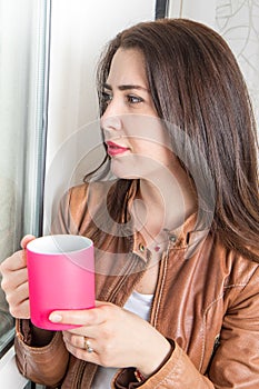 Young Woman Enjoying her morning coffee or tea, Looking Out the Window