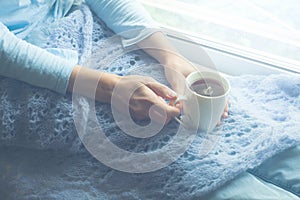 Young Woman Enjoying her morning coffee or tea, Looking Out the Window. Beautiful romantic unrecognizable girl drinking hot