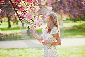 Young woman enjoying her walk in park during cherry blossom season on a nice spring day