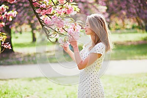 Young woman enjoying her walk in park during cherry blossom season on a nice spring day