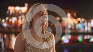 Young Woman Enjoying Music with Headphones at Night in the City