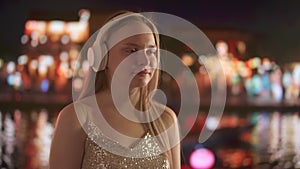 Young Woman Enjoying Music with Headphones at Night in the City