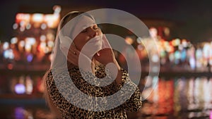 Young Woman Enjoying Music with Headphones at Night in the City