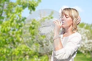 Young woman is enjoying a peaceful moment in a park or garden drinking water
