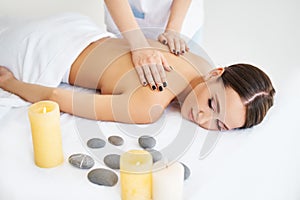 Young woman enjoying relaxing back massage at spa salon