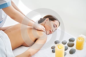 Young woman enjoying relaxing back massage at spa salon