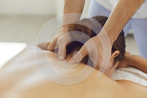 Young woman enjoying relaxing remedial body massage done by professional masseur