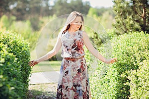 Young woman enjoying spring in the green field with blooming trees