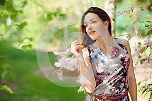 Young woman enjoying spring in the green field with blooming trees