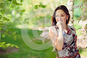 Young woman enjoying spring in the green field with blooming trees