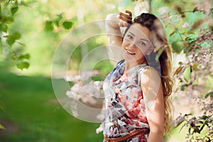 Young woman enjoying spring in the green field with blooming trees