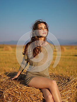 Young woman enjoying summer breeze hay stack photo