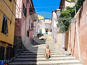 Young woman enjoying the sun in an alley of a small rural medieval village