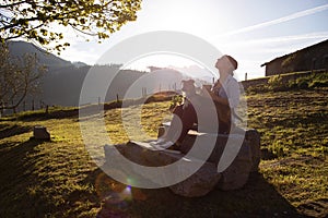 Young woman enjoying the sun rays at sunset with a cup of coffee in her hand and accompanied by her dog bodeguero. rural area.