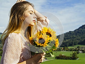 Young woman enjoying the sunlight holding sunflowers