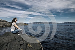 Young woman is enjoying the sunny day on the seaside of Norway