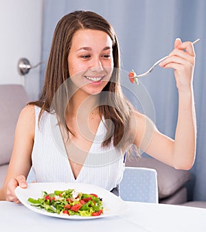 Young woman is enjoying tasty green salad