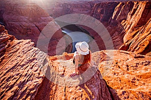 Young woman enjoying view of Horseshoe bend, Arizona. Horseshoe Bend, canyon and Colorado river at sunset. Famous hiking