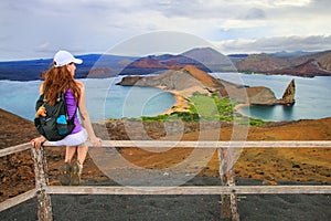 Young woman enjoying the view of Pinnacle Rock on Bartolome island, Galapagos National Park, Ecuador.