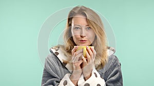 Young woman enjoying a warm cup of tea, cozy morning in polka dot robe