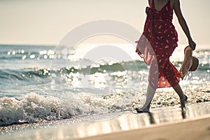 A young woman enjoys barefoot walk through the shallow on the beach. Summer, beach, sea, vacation