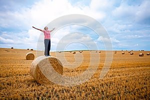 young woman enjoys freedom on a straw bale