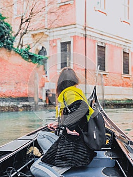 A young woman enjoys a gondola ride and making photo in the canals of Venice.