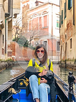 A young woman enjoys a gondola ride and making photo in the canals of Venice.