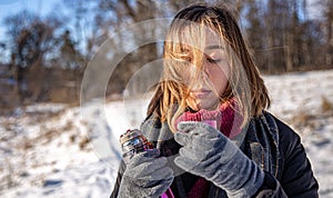 A young woman enjoys a hot drink from a thermos on a walk in winter.